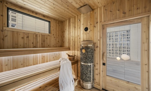 Scandinavian Cedar Sauna at Gibson Point | Timbre Bathhouse Experience in Boston Warm cedar sauna with stone heater and soft lighting at Gibson Point, echoing Scandinavian bathhouse traditions within the Timbre thermal wellness retreat
