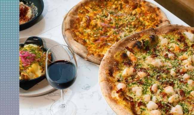 A perfect fit for the whole family at Gibson Point Close-up of wood-fired pizzas, cheesy skillet dish, red wine, and meatballs at Mila’s, a modern waterfront restaurant at Gibson Point in Revere, MA